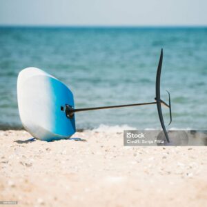 Windsurfer on the board. Trend sport wing surfing sports equipment, water sports in blue with sails, on the beach in the background water