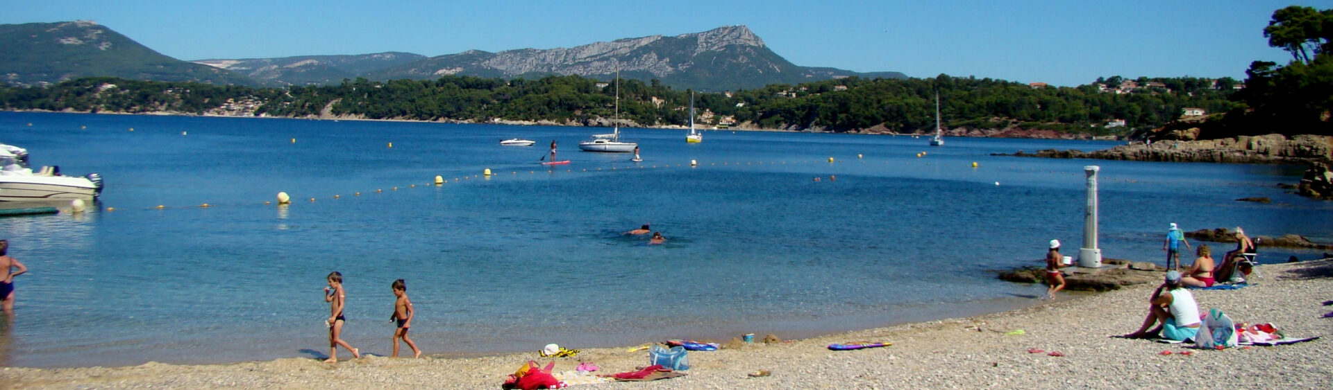 Vue de la plage des Oursinières au Pradet avec galets, mer turquoise et rochers en arrière-plan