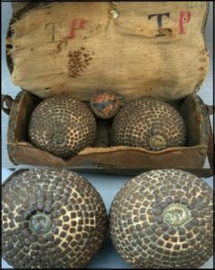 Gros plan sur deux boules de pétanque anciennes en métal avec des clous en étoile, posées sur un meuble en bois, symbolisant l'esprit de la Provence dans un gîte de vacances au Pradet.