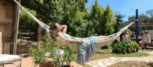 Jeune femme se relaxant dans un hamac dans le jardin verdoyant d'un gîte au Pradet, Var.