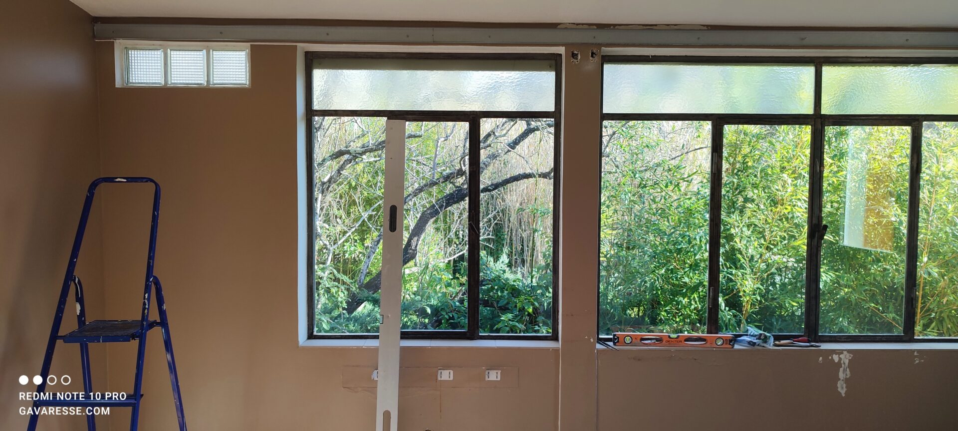 Installation du premier montant métallique horizontal au-dessus des grandes vitres du salon pour la structure du plafond suspendu.