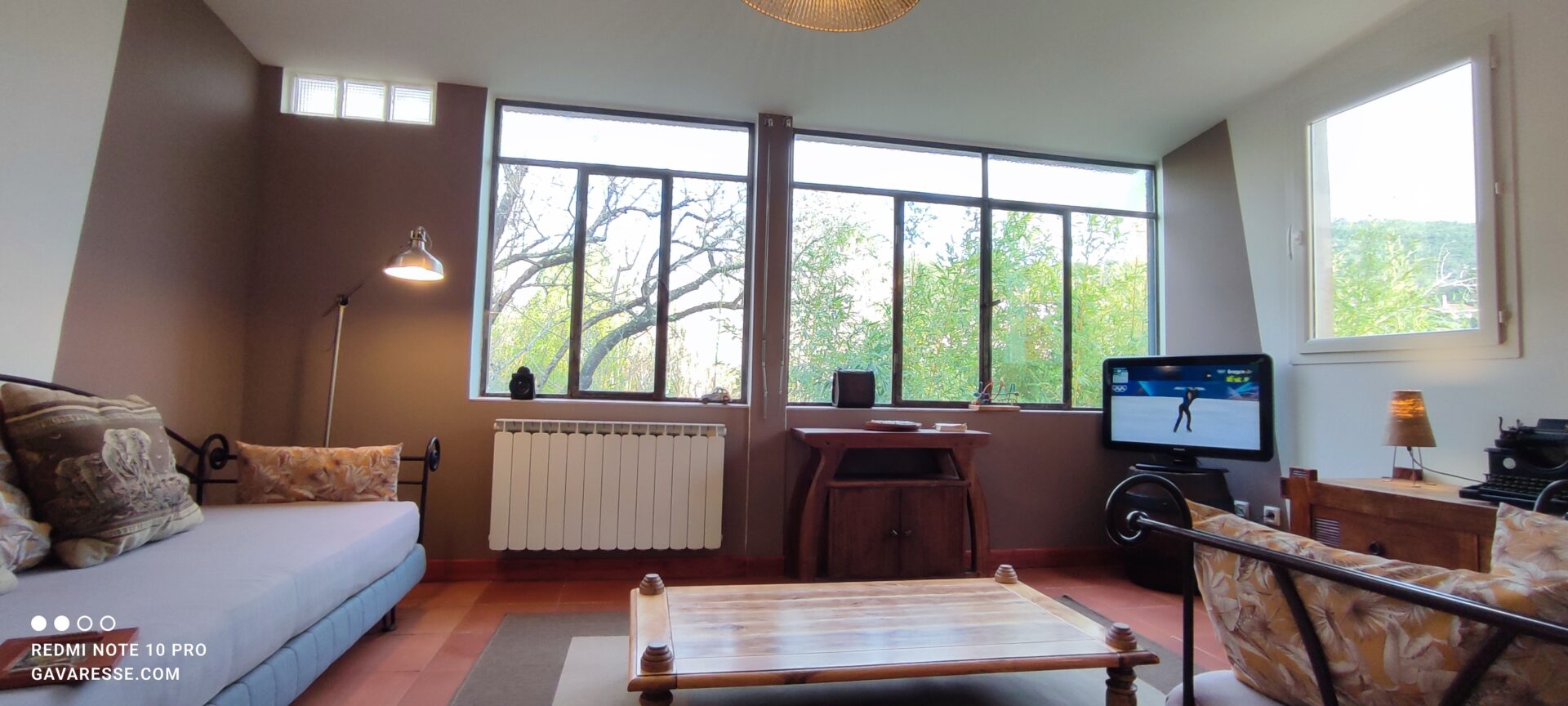 Sol en terre cuite restauré et nourri à l'huile de lin dans le salon du gîte l'Orangeraie. La pièce est meublée avec un divan, une table basse en bois et une télévision.